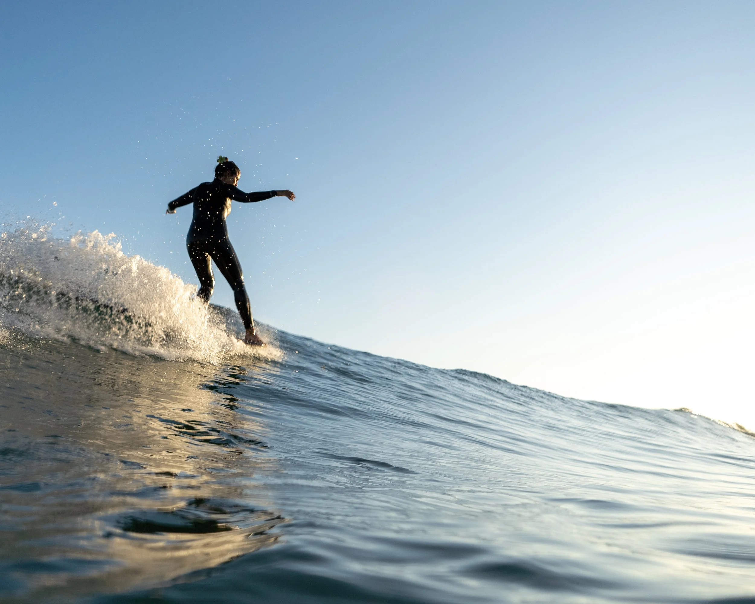 A woman surfing on a wave in the ocean during sunset