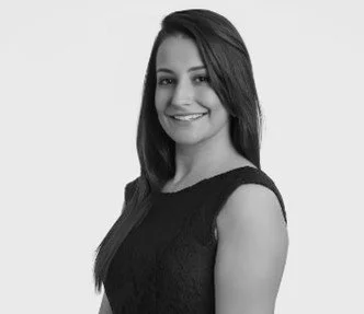 Black and white photo of a smiling woman with medium-length dark hair, wearing a sleeveless top.