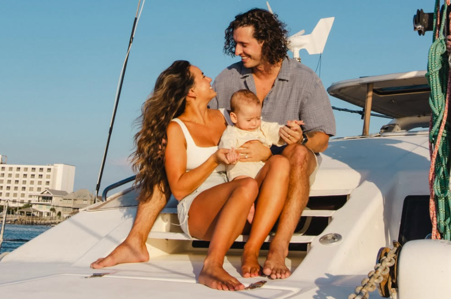 Mackenzie and Josh Dajani with their baby on the bow of their catamaran