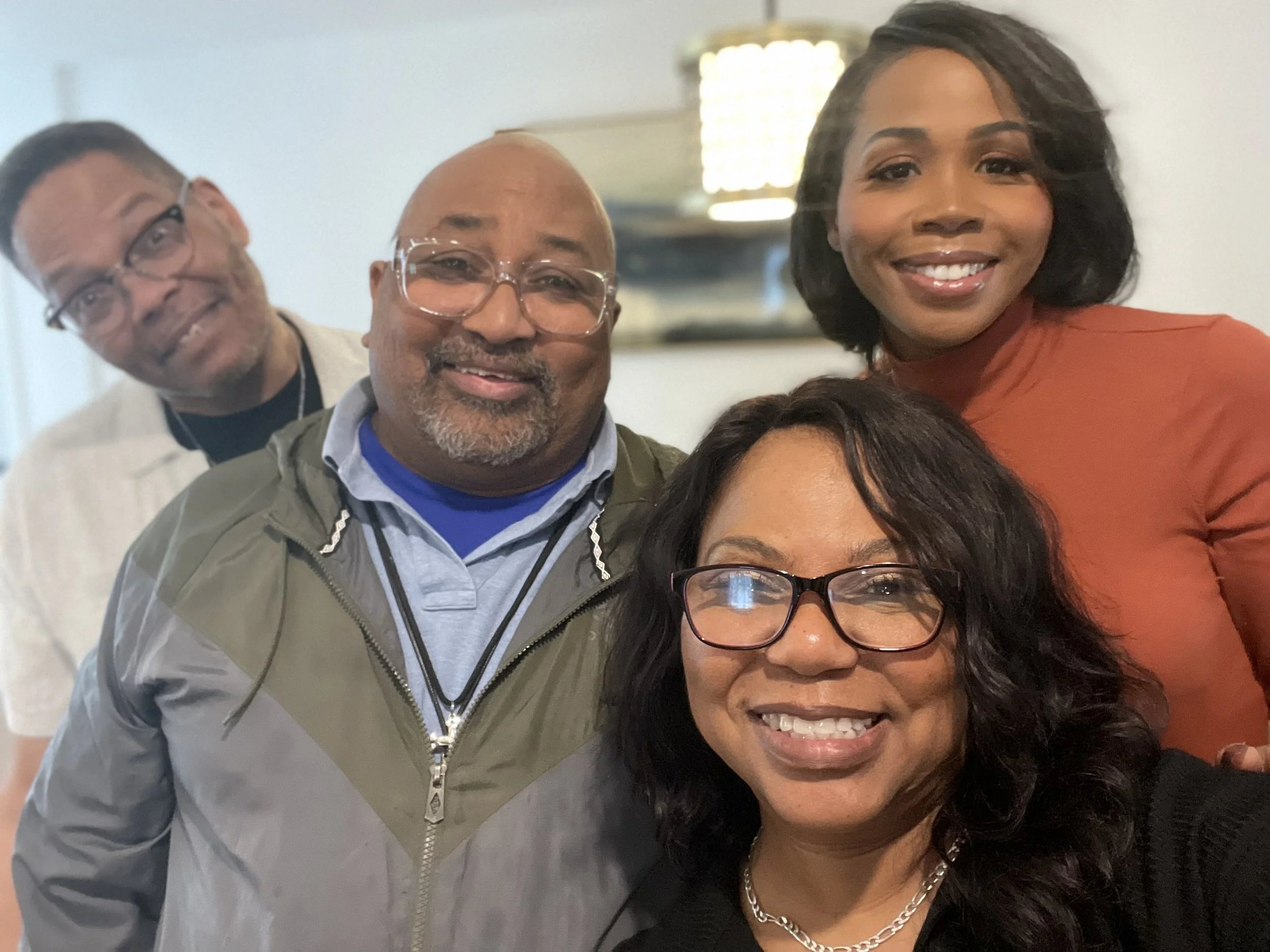 A group of five diverse people smiling for a selfie indoors.