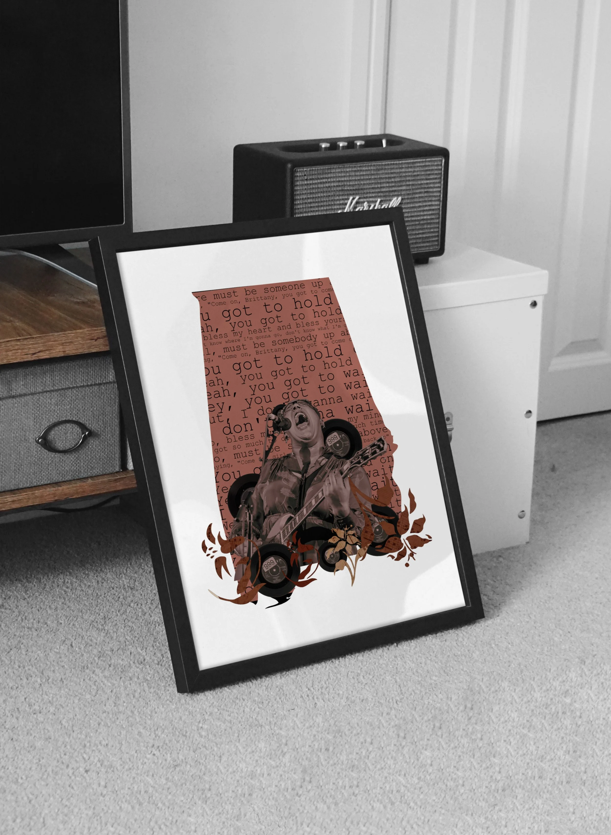 A framed poster leaning against a piece of furniture, featuring a person singing and playing the guitar, with layered text and graphic design elements in a monochrome color scheme.