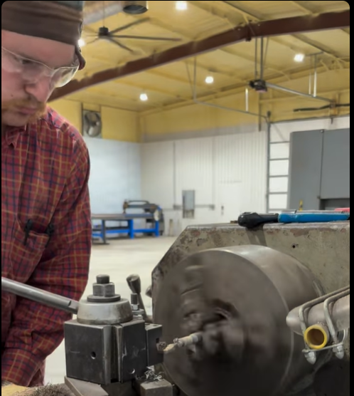 A metal lathe in a workshop for machining custom bolts rods pins bolts and shafts.