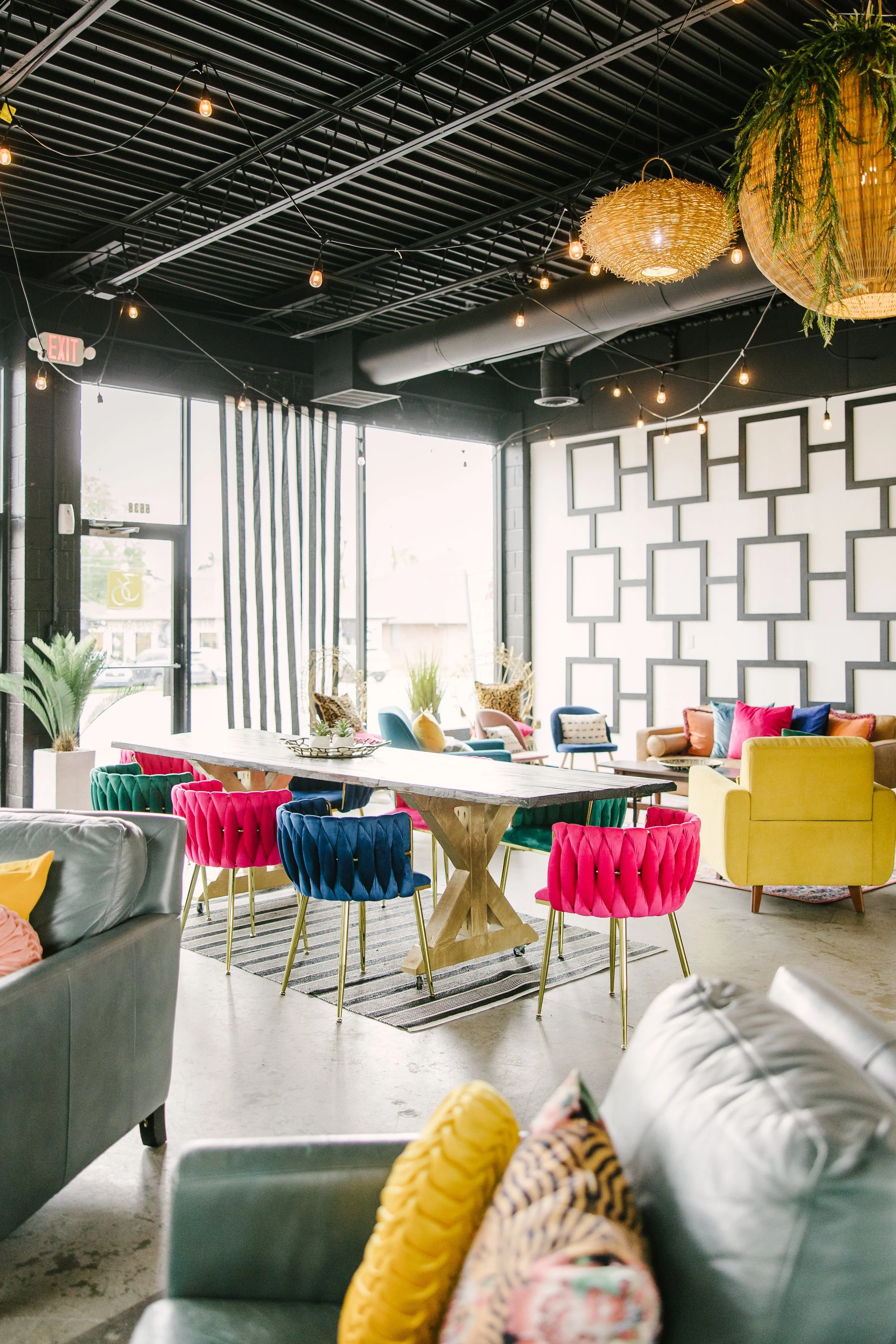 Colorful modern lounge with a variety of chairs and sofas, large windows, and decorative lighting fixtures.