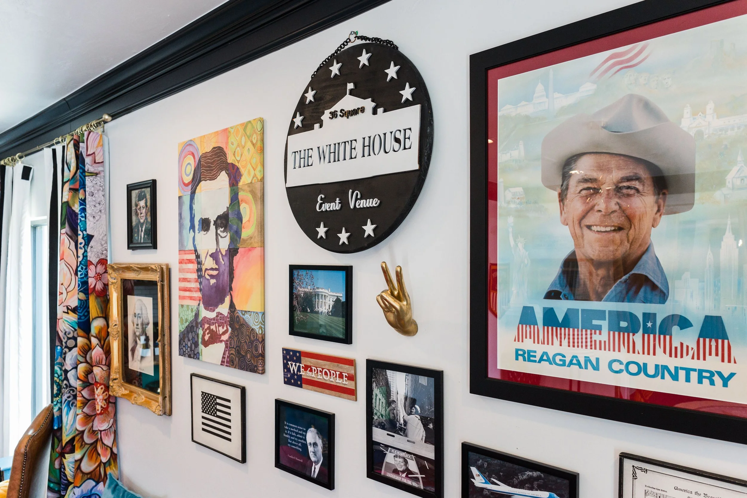 Decorative wall with artwork and memorabilia, including a large Roosevelt portrait, a 'Make America Great Again' poster, Abraham Lincoln silhouette art, and a 'The White House' event venue sign.