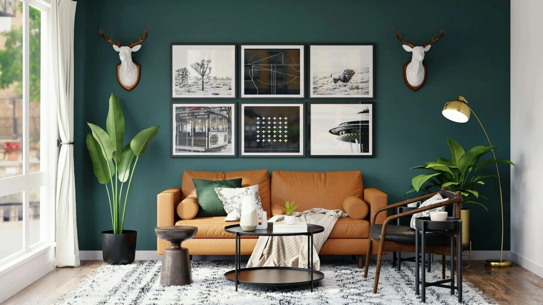 Airbnb example - Living room with teal accent wall, tan leather sofa, black and white framed art, deer head wall mounts, large green plants, black coffee table, side table, modern floor lamp, patterned rug, and large window with white curtains.