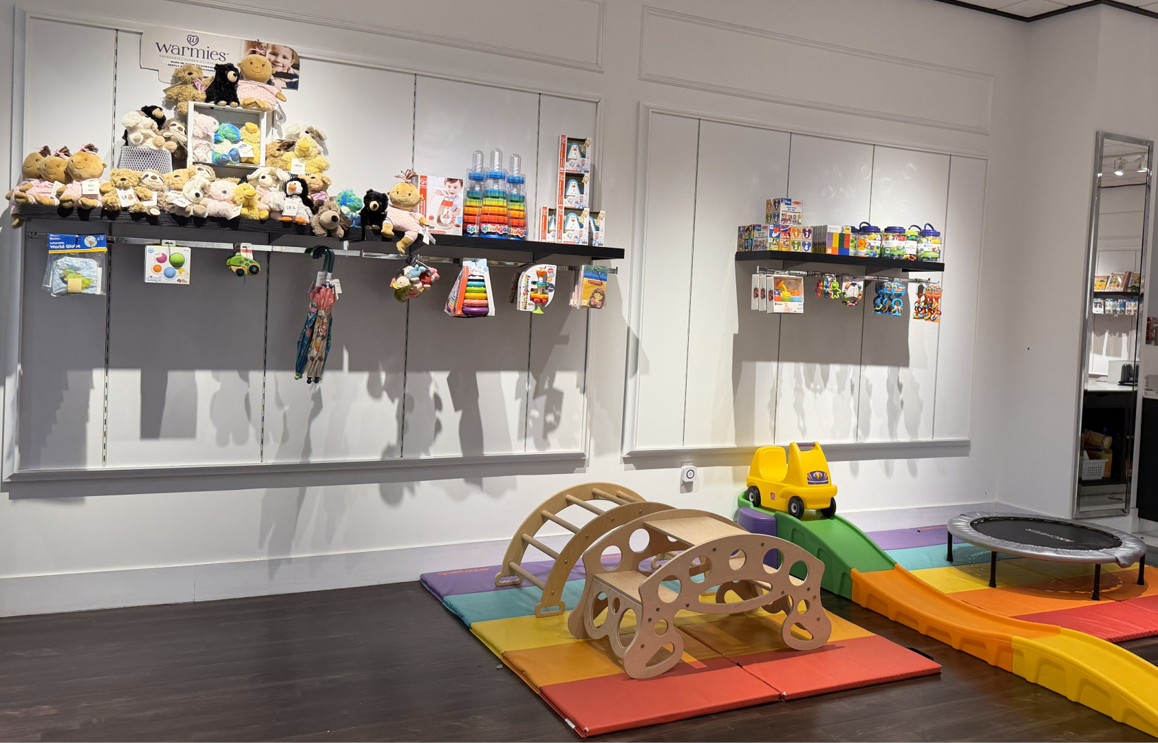 A mural featuring a cartoon person holding a red balloon against a blue sky with white clouds, inside a toy store with shelves of toys and games.