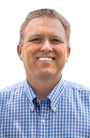 A man with short, light hair, smiling, wearing a blue checkered shirt, against a plain white background.