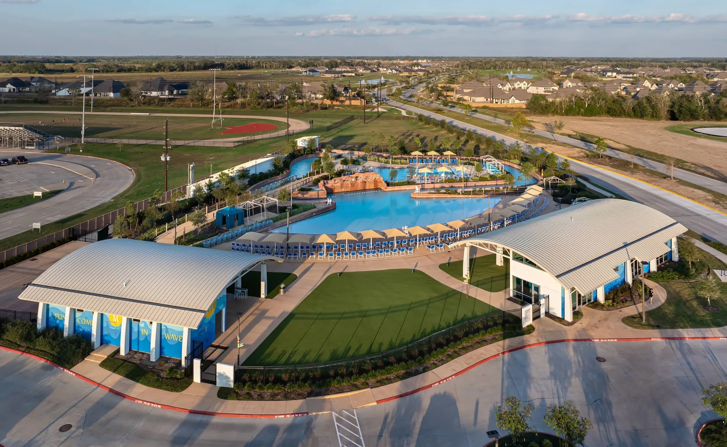 A commercial landscape contractor inspecting a retention pond edge with trimmed greenery and stonework as part of erosion control in Harris County, TX
