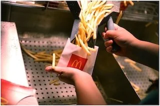 Person holding a container of French fries
