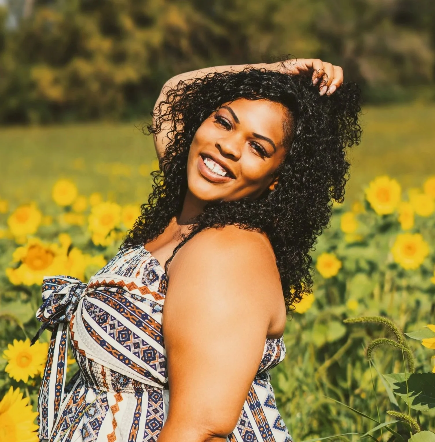 Angel with curly black hair smiling in a field of yellow flowers.