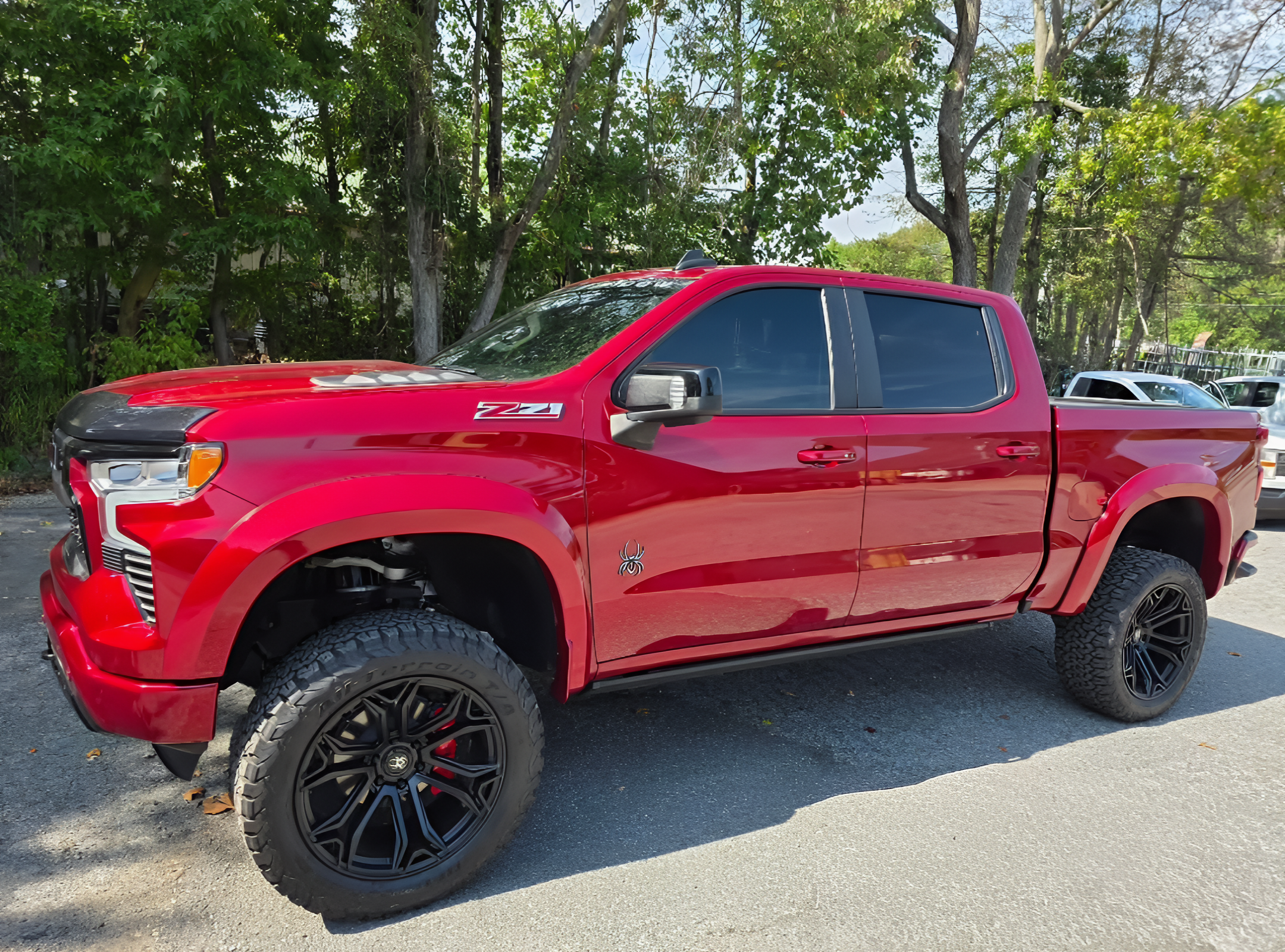 Red pickup truck parked on a street with trees in the background.