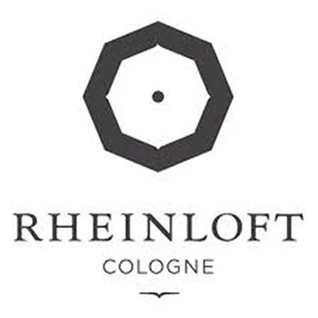 Ein Logo mit einem schwarzen, sechseckigen Rahmen und einem kleinen schwarzen Punkt in der Mitte, darunter der Text "Rheinloft Cologne".