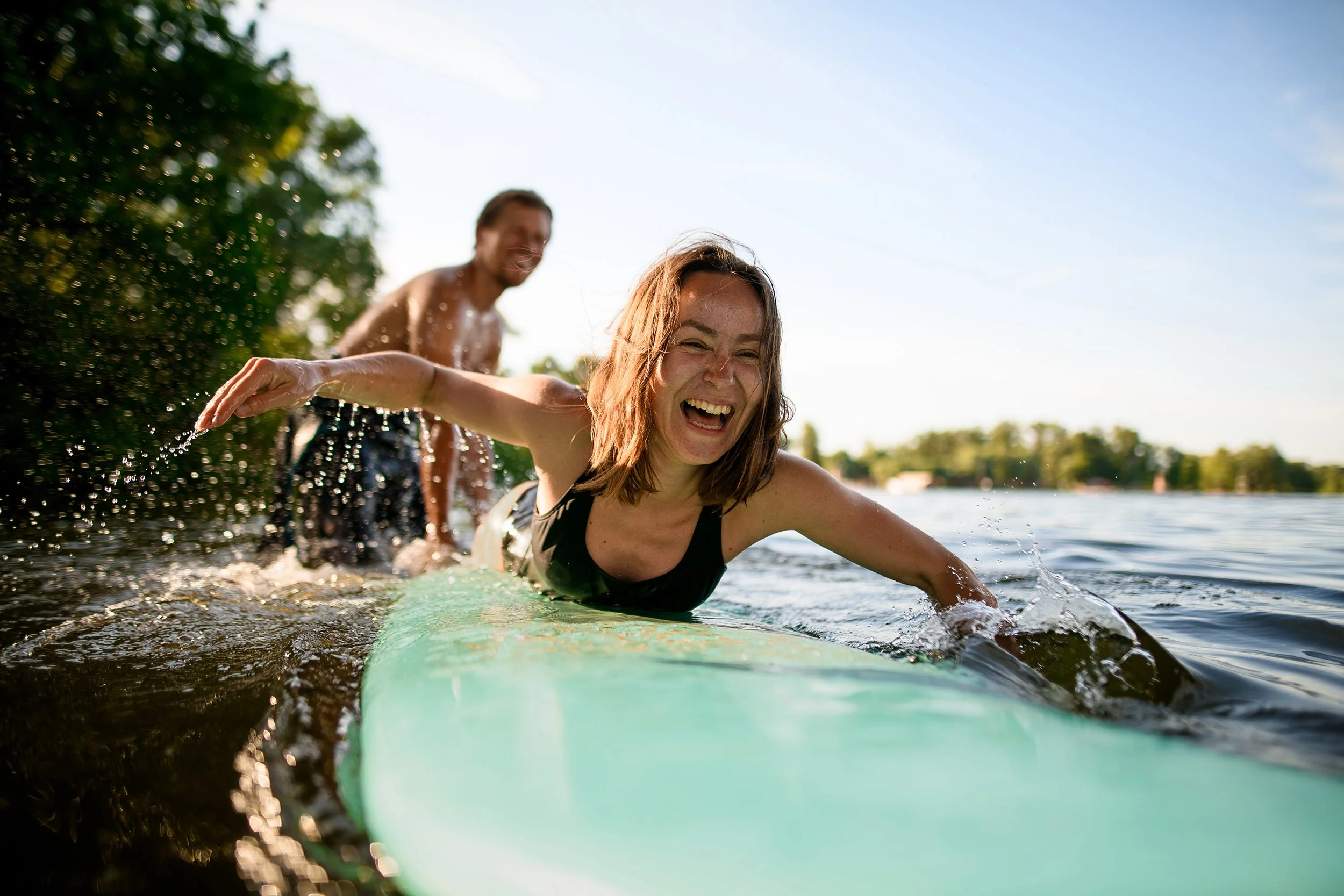 A happy couple paddle boarding with no back pain.