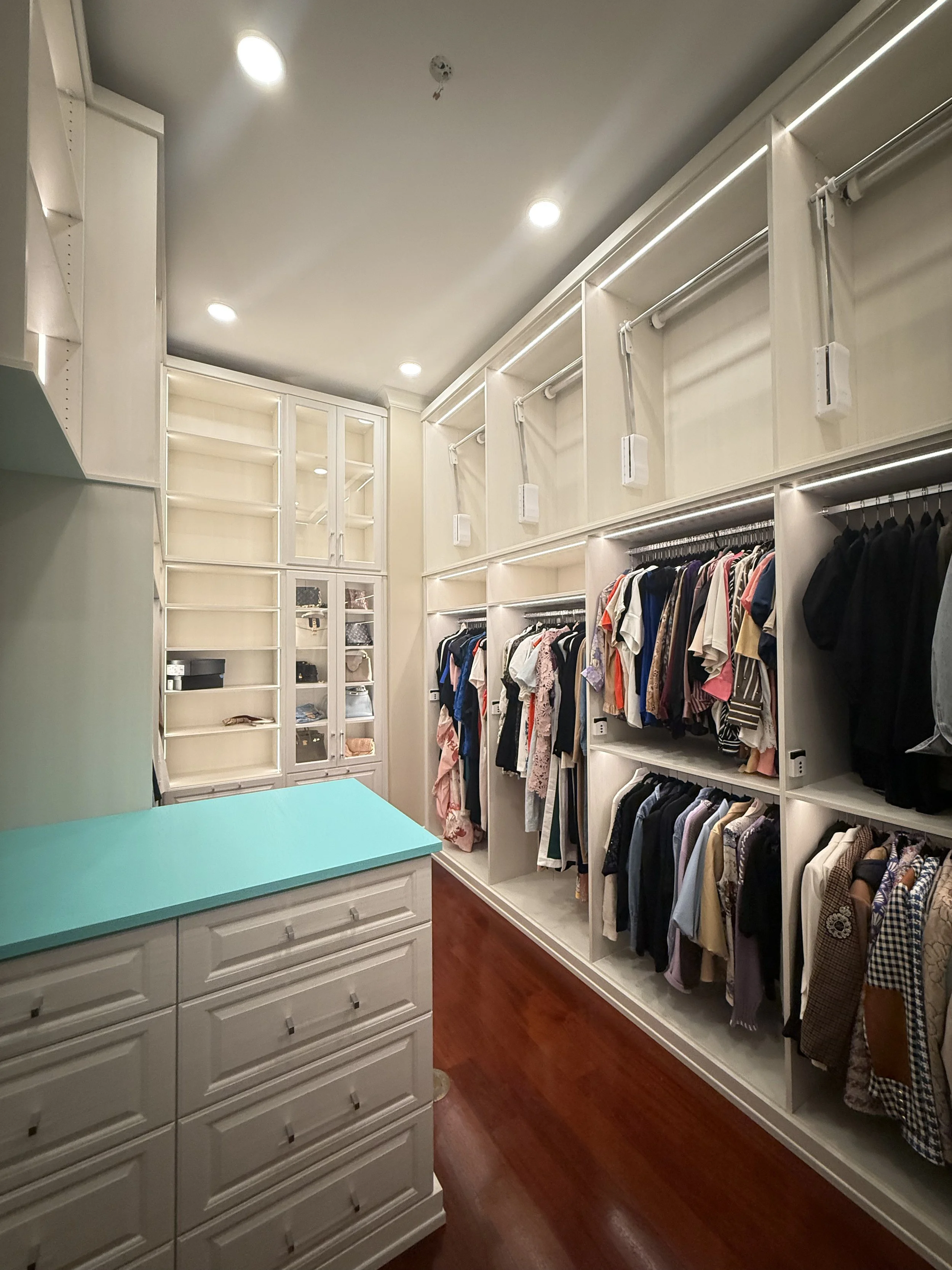 Modern kitchen with white cabinets, marble countertops, a wood herringbone floor, pendant lights, and a sliding glass door.