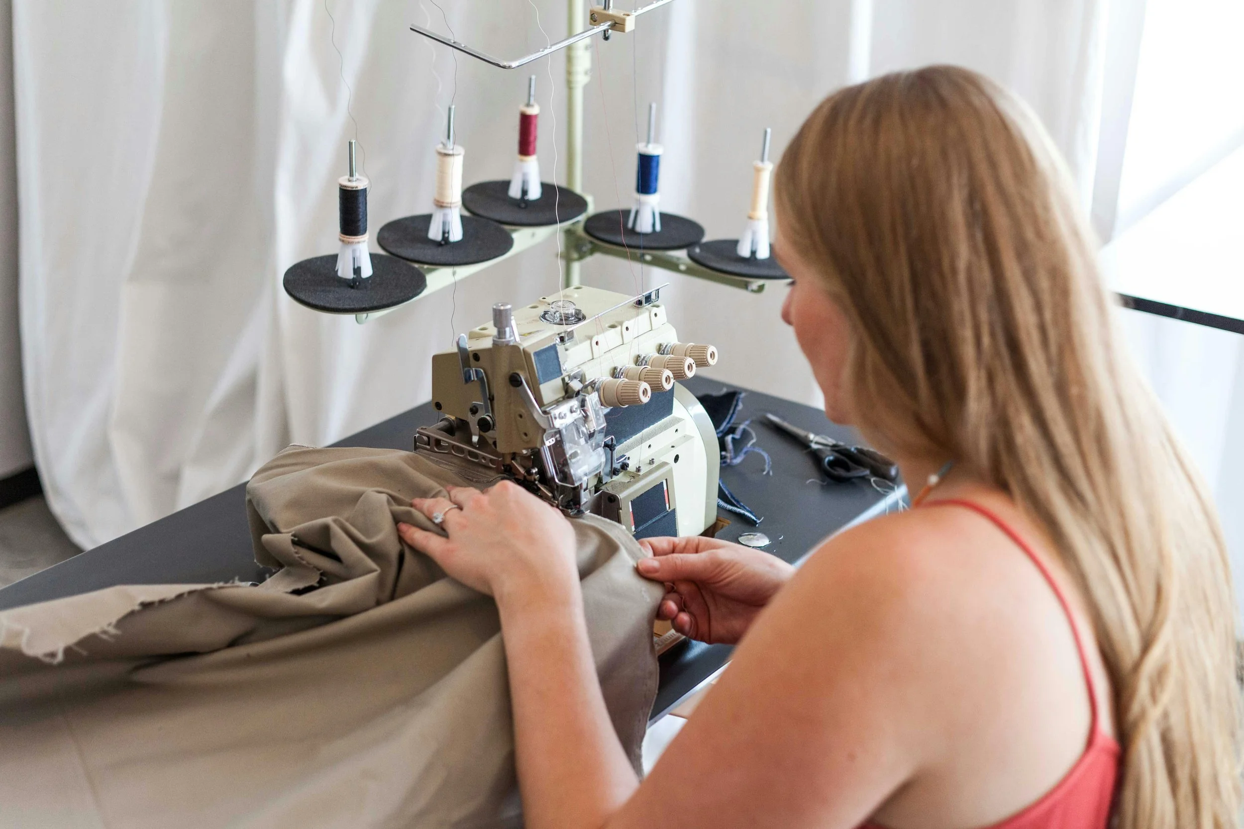 Seamstress operating a sewing machine during custom clothing manufacturing.