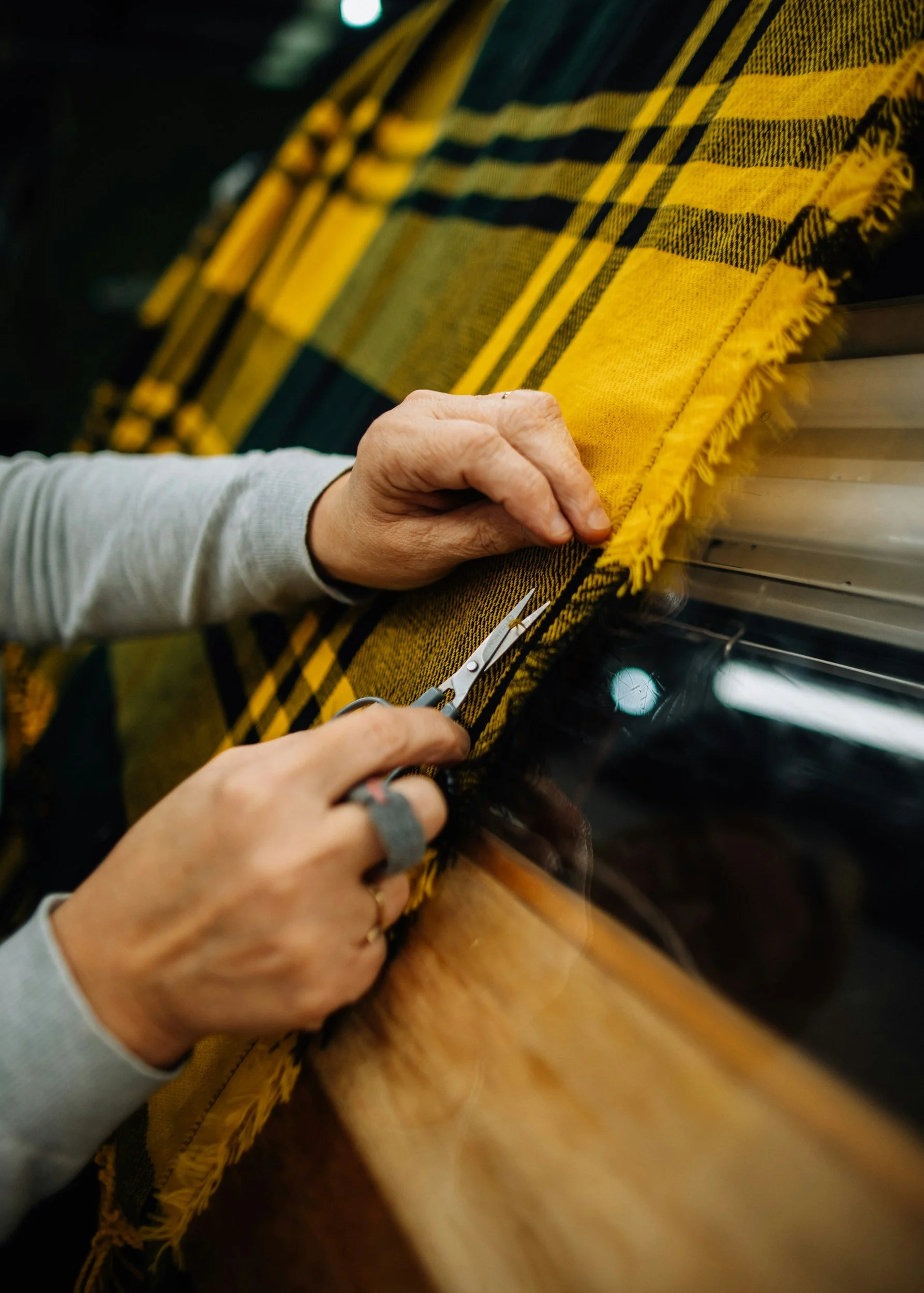 Hand-cutting patterned fabric at a cut-and-sew worktable during garment production.