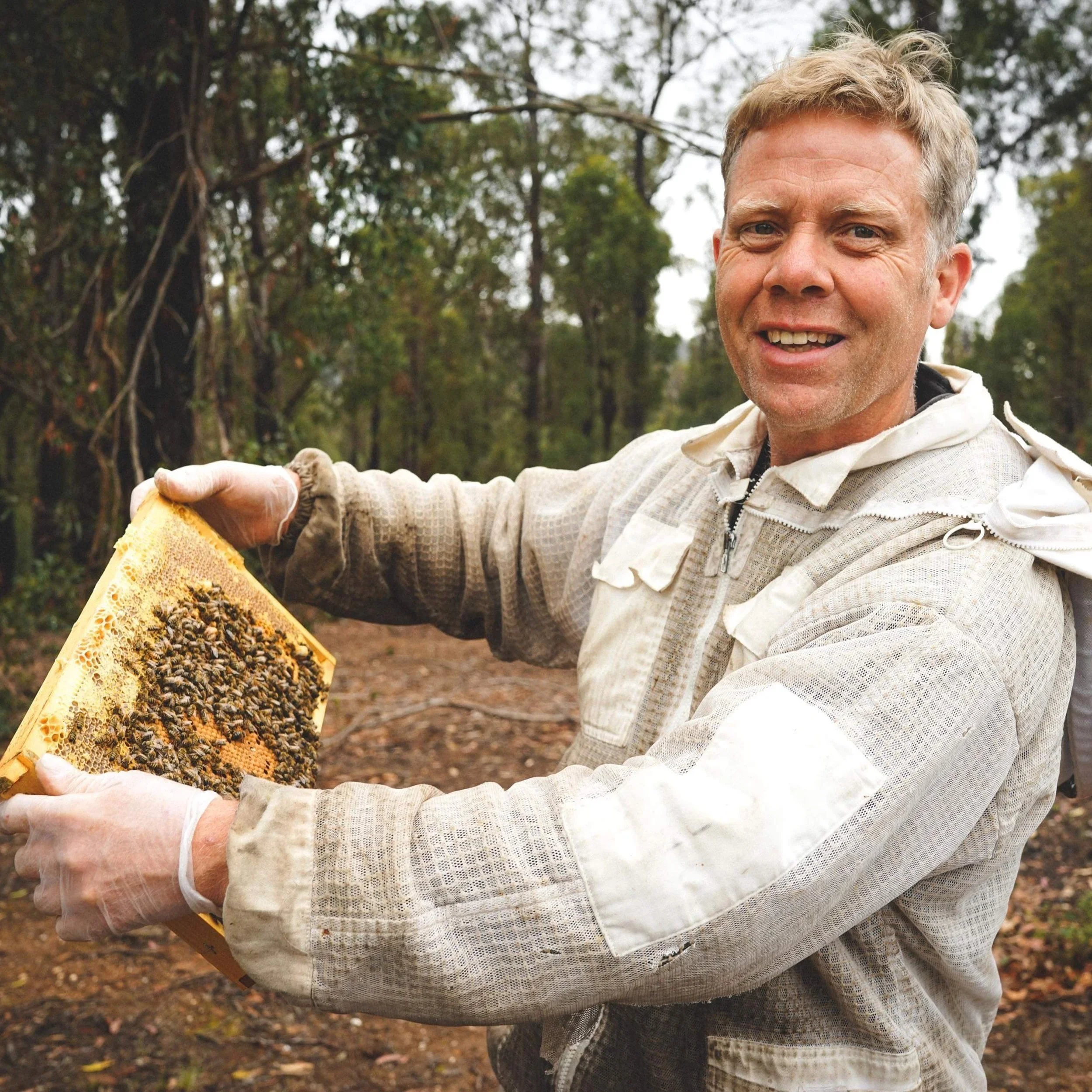 Peter Gatehouse with a honeycomb frame with bees.