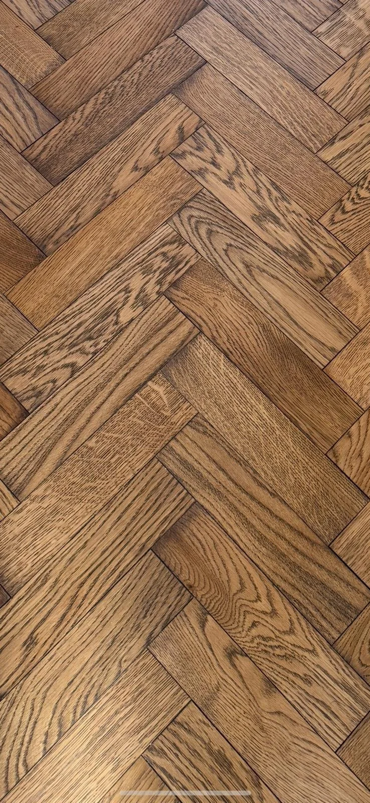 Close-up of a wooden parquet floor with a herringbone pattern.