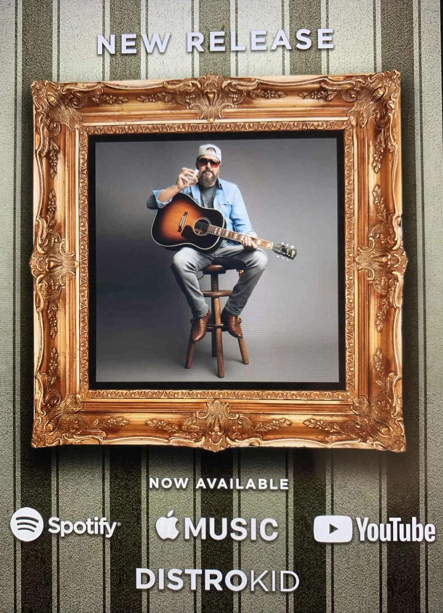 Advertisement for a new music release featuring a man with sunglasses, a beard, and a cap, sitting on a stool with a guitar, holding a glass of drink.