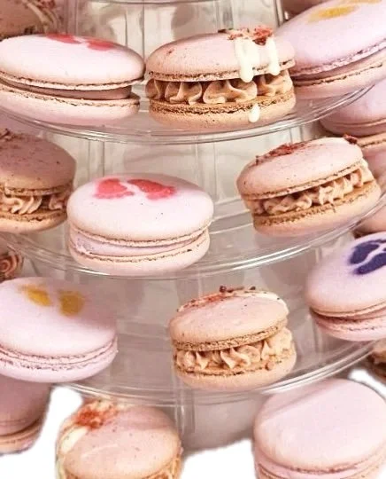 Assorted macarons on a clear, tiered display stand.