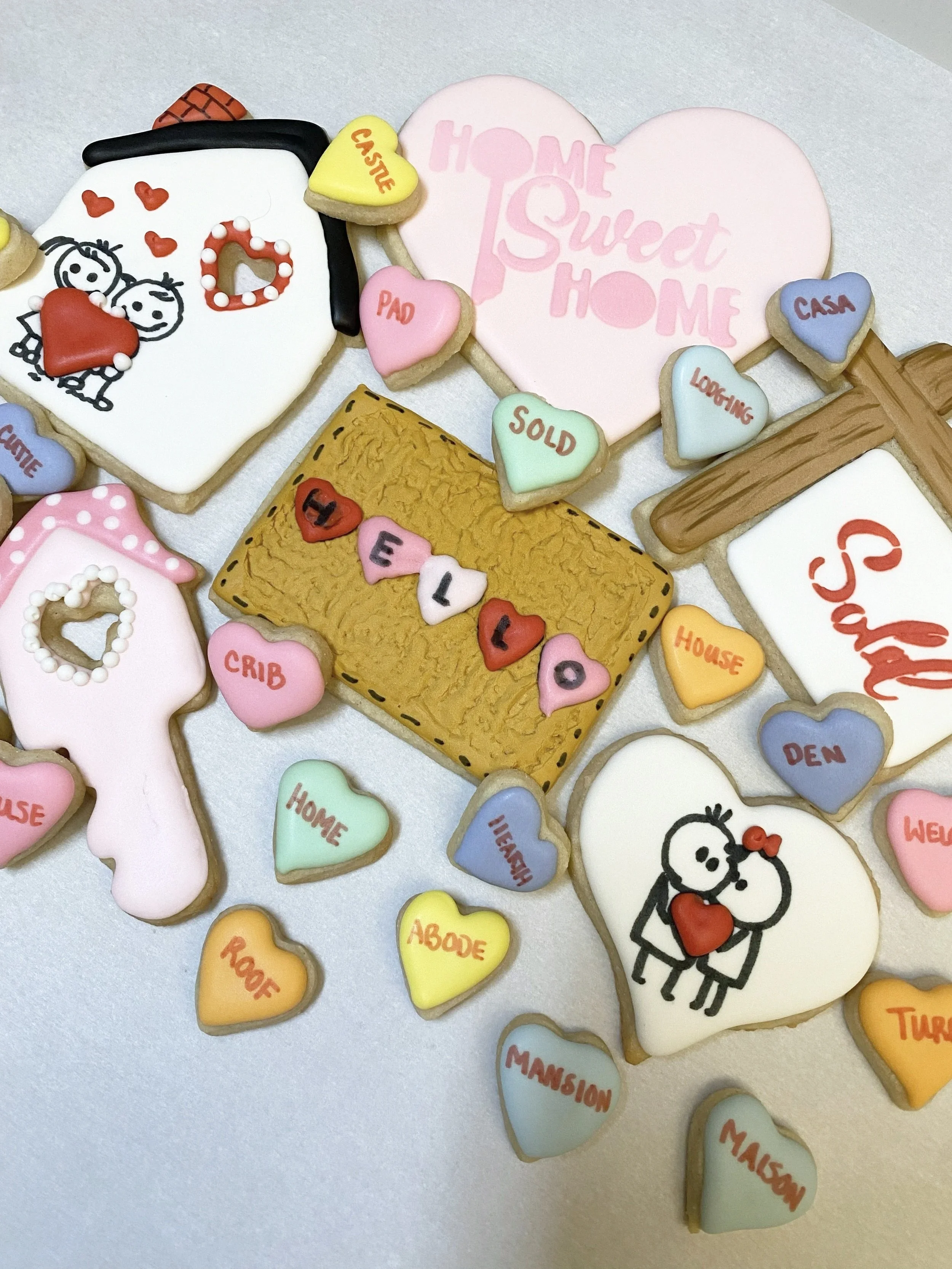 Decorated home-themed cookies including hearts, a house, a family, and words like 'Home Sweet Home' and 'Love' in various pastel colors.