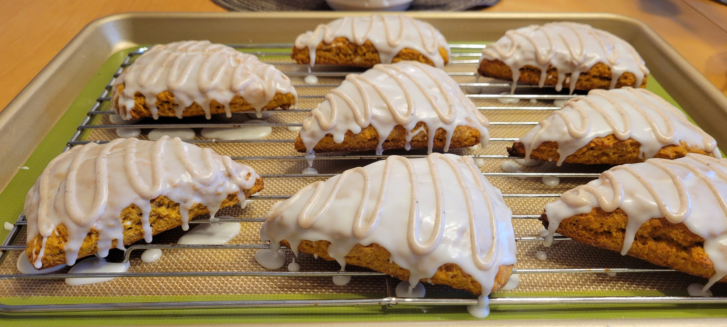 Freshly baked bar cookies with white icing and caramel drizzle on a cooling rack