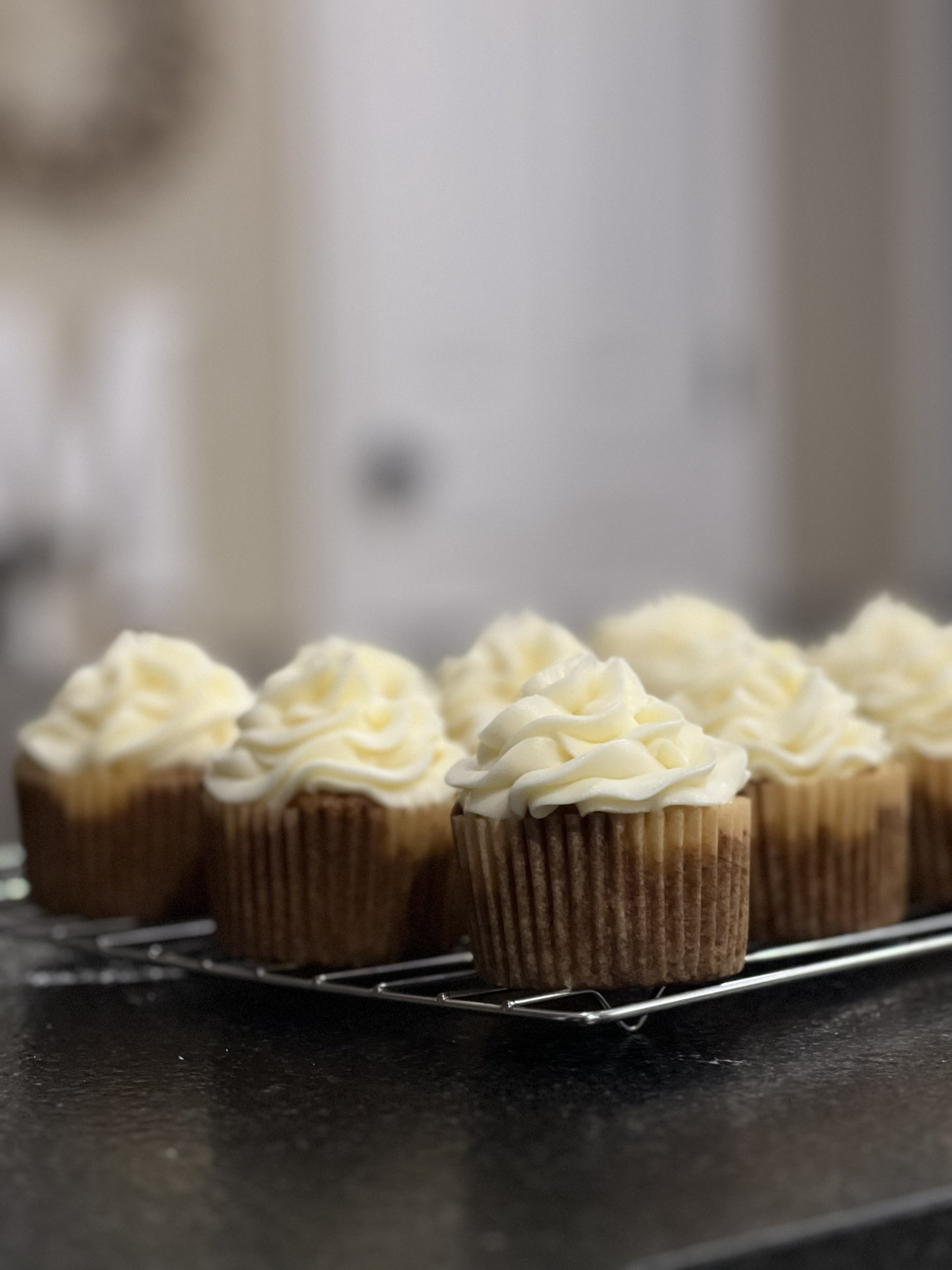 Chocolate cupcakes with white frosting on a cooling rack.
