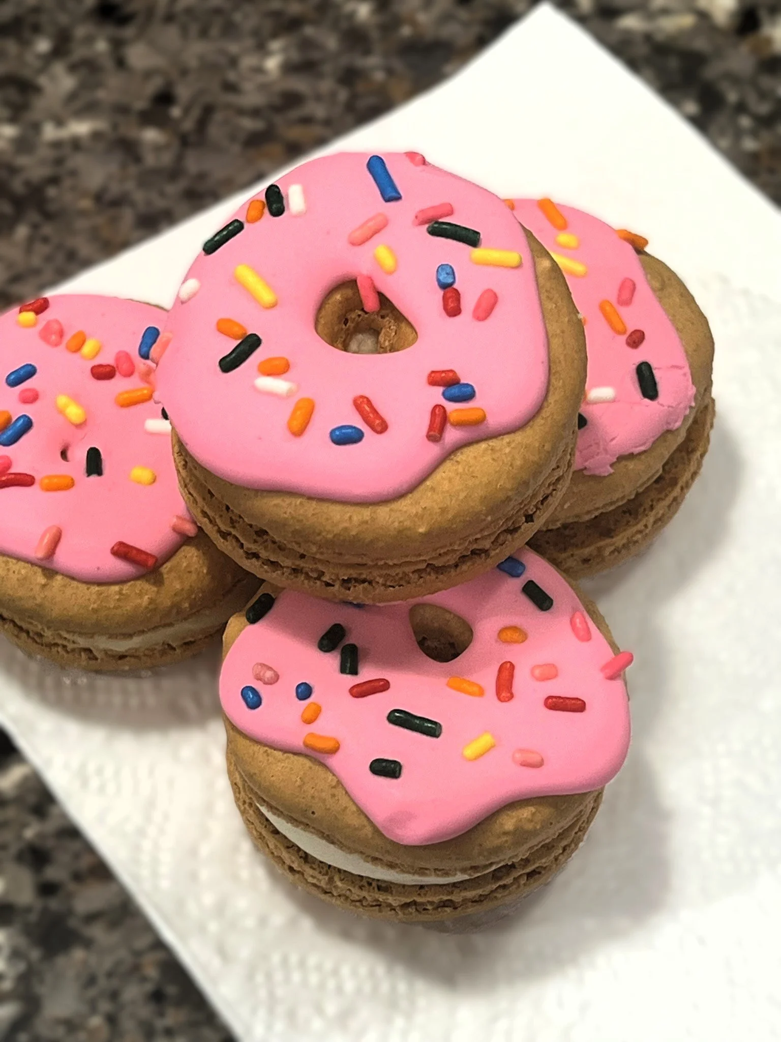 Macarons adorned in donut style icing. Links to macaron menu.