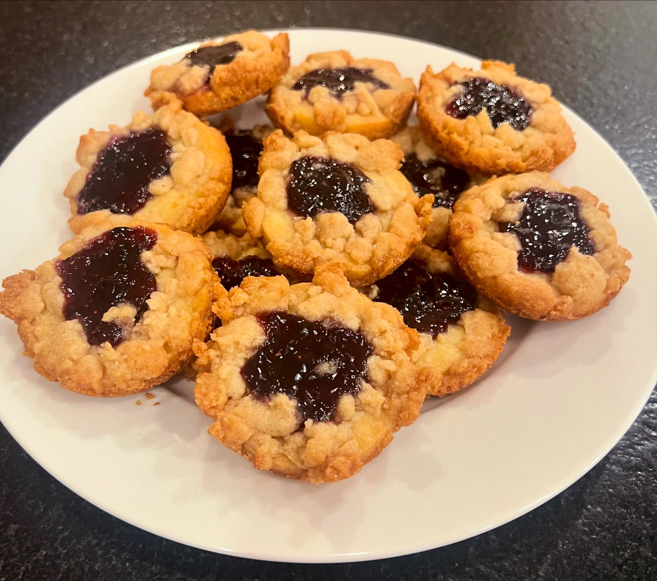 Plate of nine cherry-filled crumb-top cookies on a white plate.