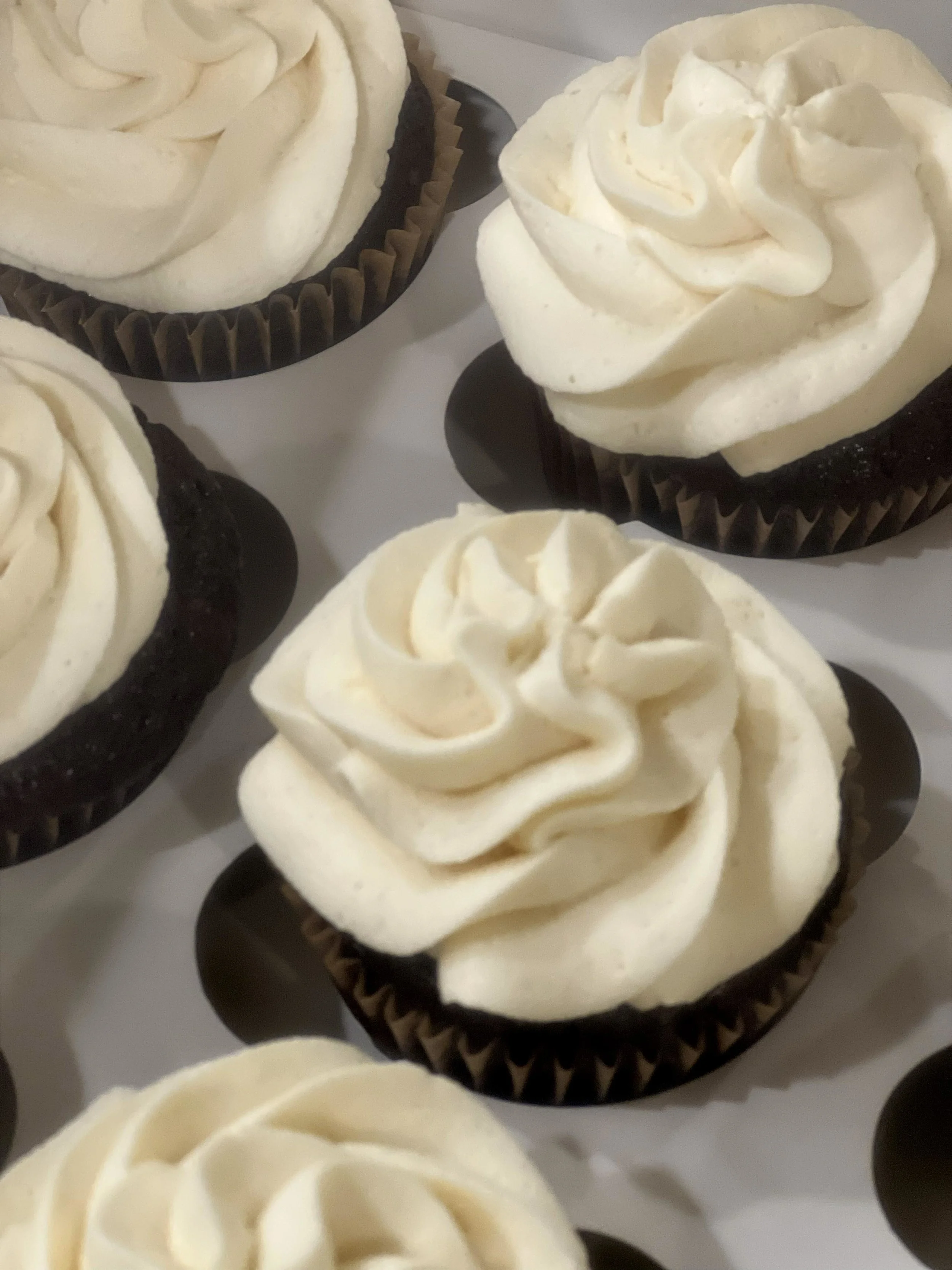 Chocolate cupcakes with white frosting piped in a swirl pattern.