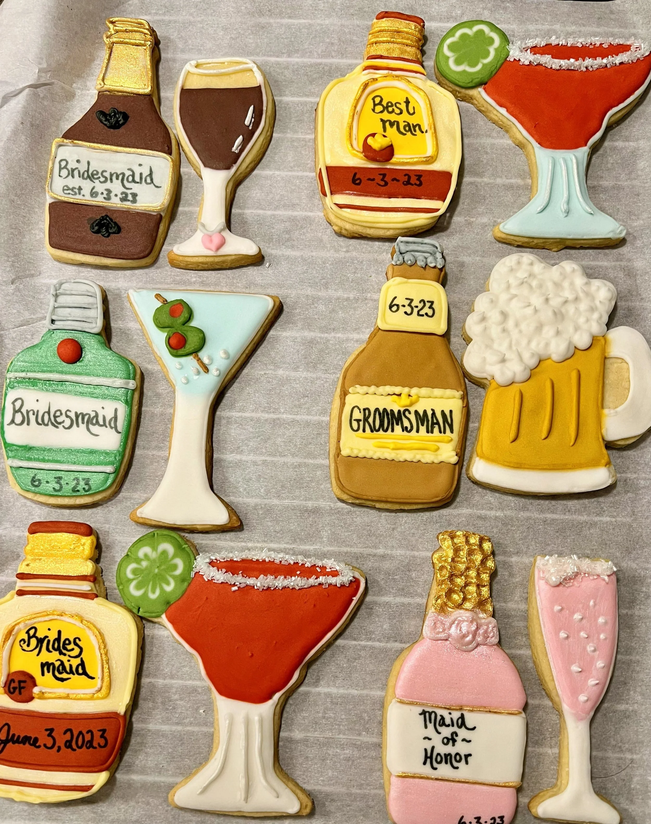 Decorated cookies themed for a wedding, including champagne bottles, glasses of champagne, and a beer mug, all with personalized messages and dates.