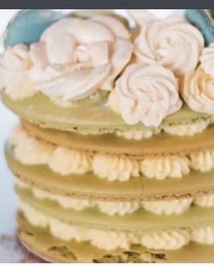 Close-up of a layered cake with white frosting and decorative roses on top.