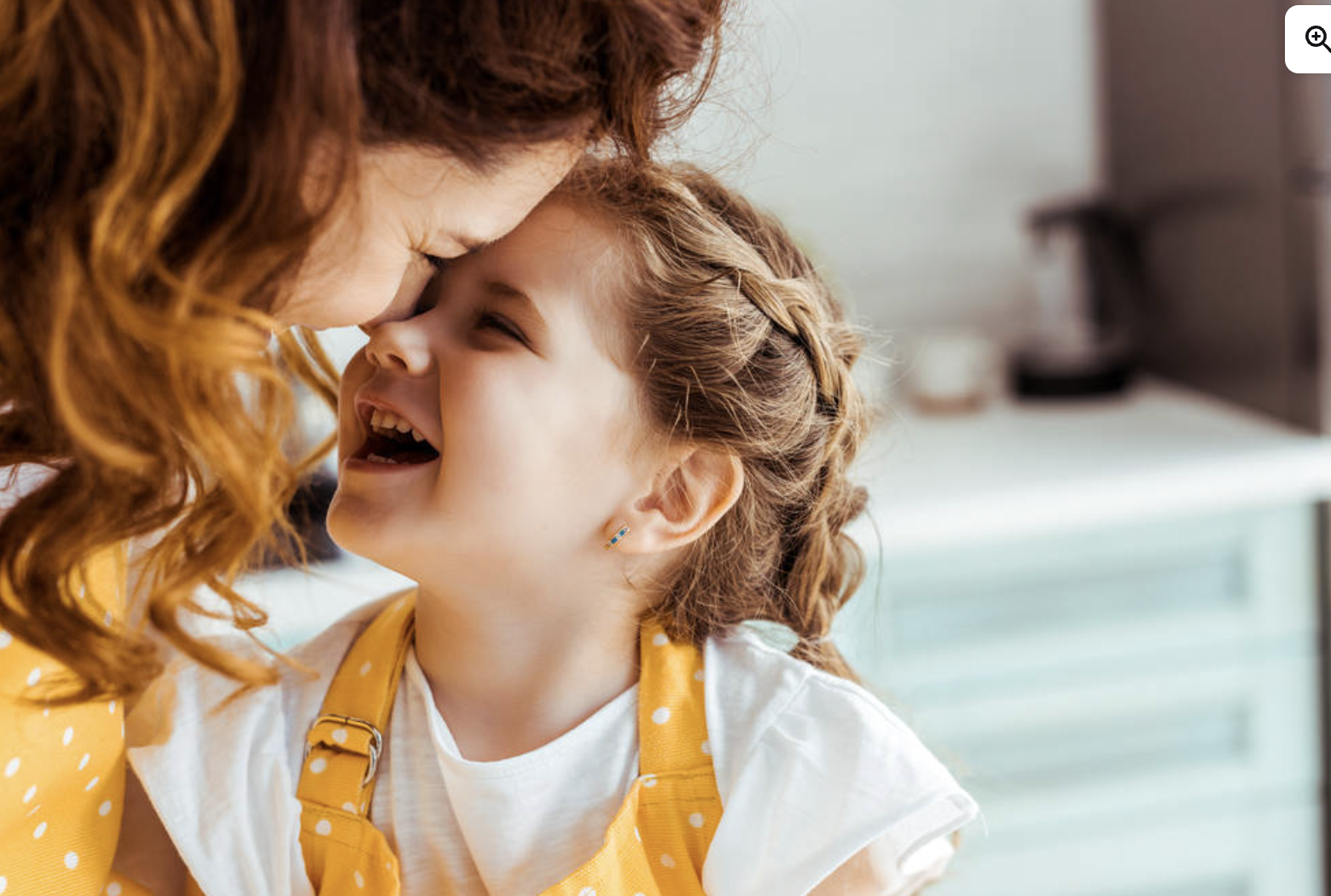 A mom and a child sharing a joyful moment in a kitchen setting.