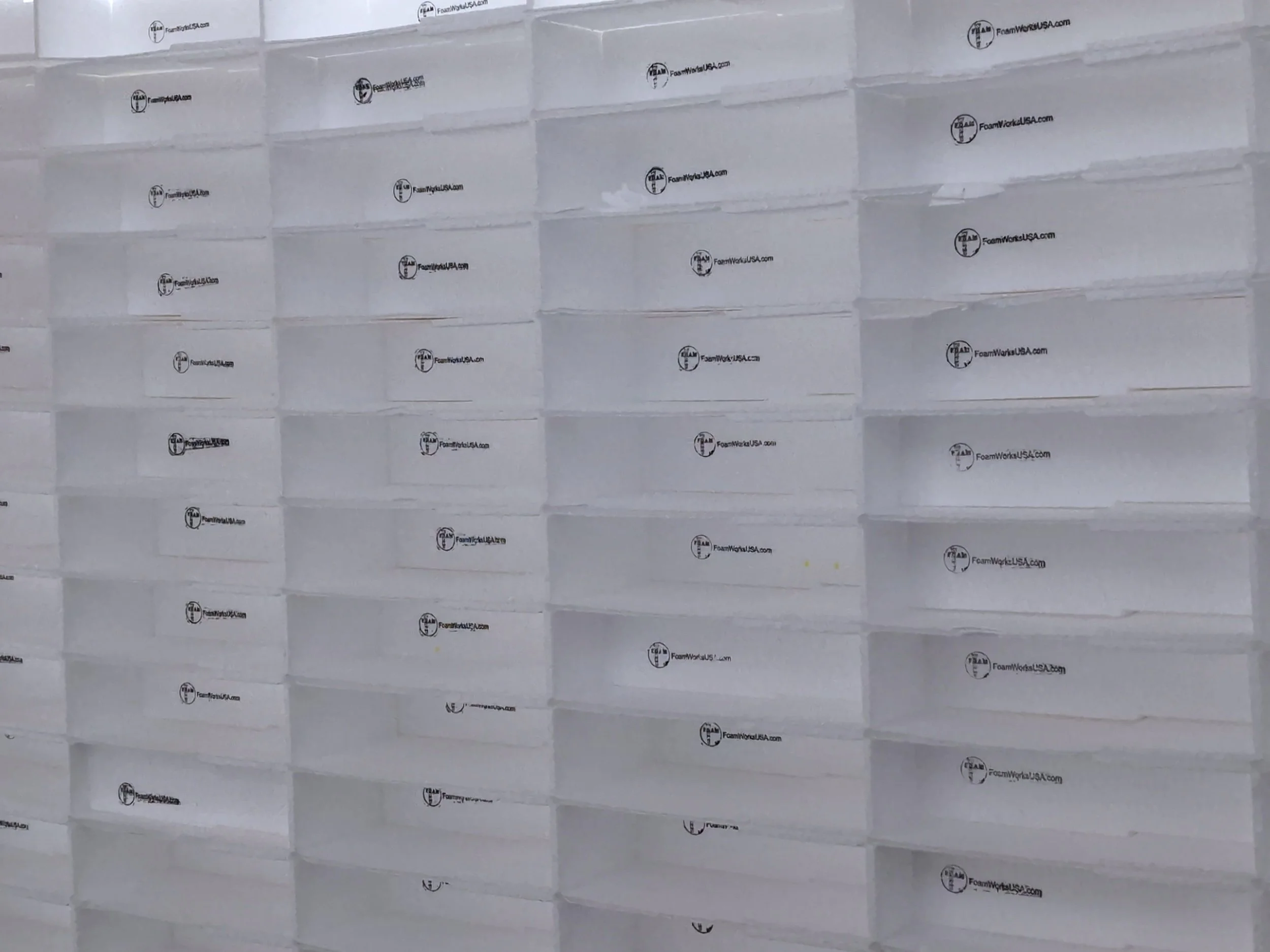 Stacked white EIFS Starters stamped with FoamWorks logo and website, pushed out of the EPS billet after the CNC Hot Wire machine cut the profiles, arranged in rows.
