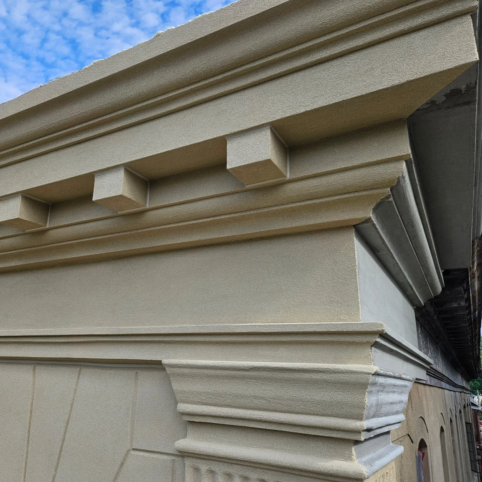 Commercial EIFS Building project featuring three FoamWorks Cornices and foam dentals installed on a wall.