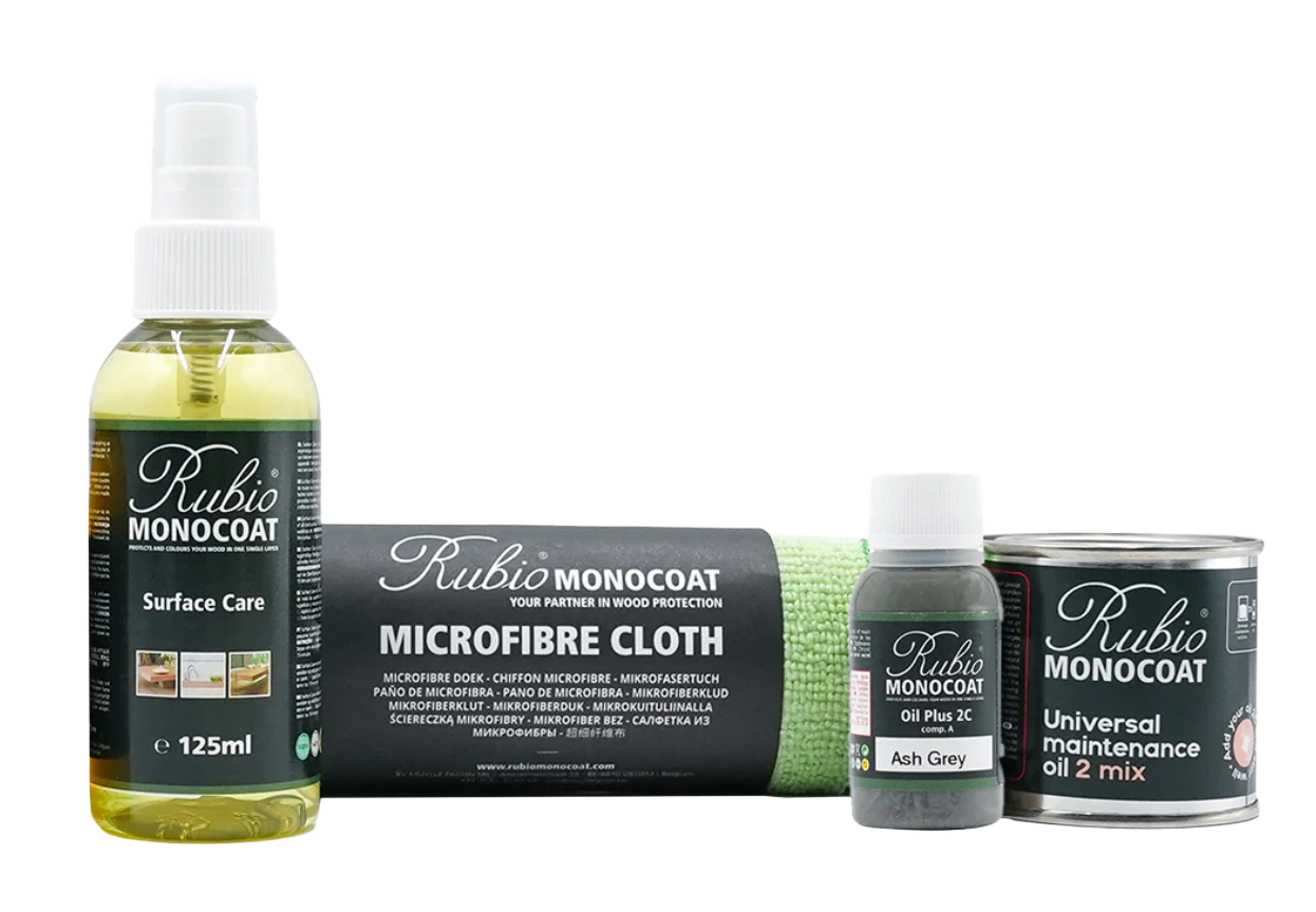 A collection of Rubio MONCOAT wood care products including a 125ml spray bottle, a microfiber cloth, a small bottle of oil plus 2C Ash Grey, and a can of universal maintenance oil in a 2-mix container.