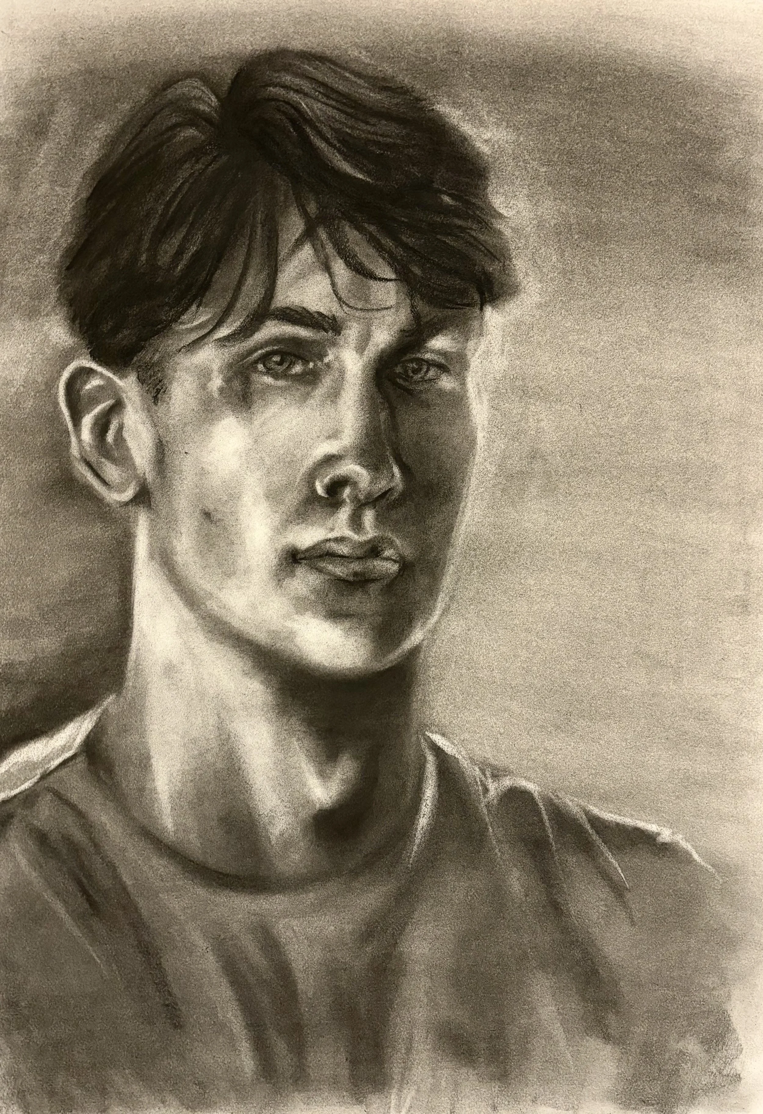 A realistic black and white portrait drawing of a young man with short, tousled hair, light eyes, and a serious expression, wearing a casual shirt.