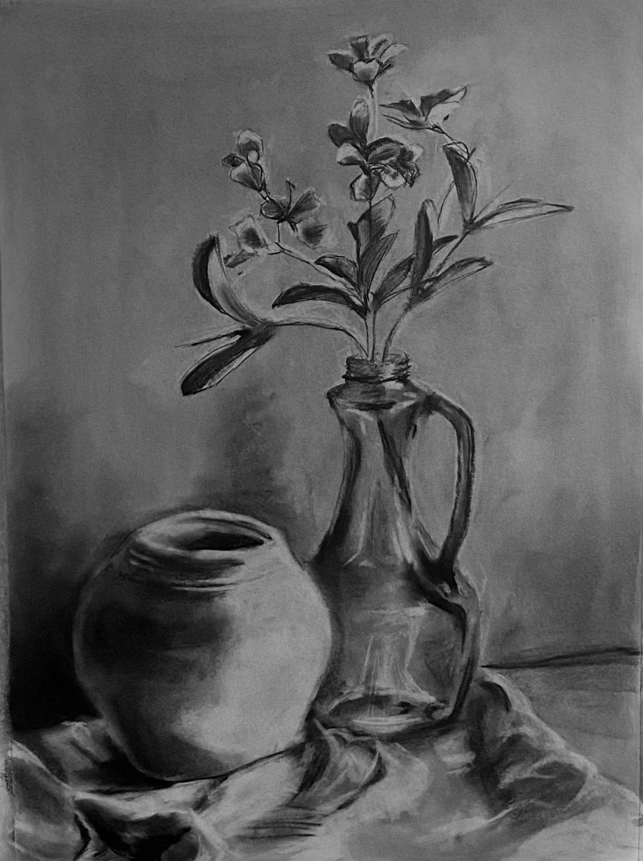 A black and white still life drawing of a flower in a glass vase and a ceramic pot on a cloth-covered surface.