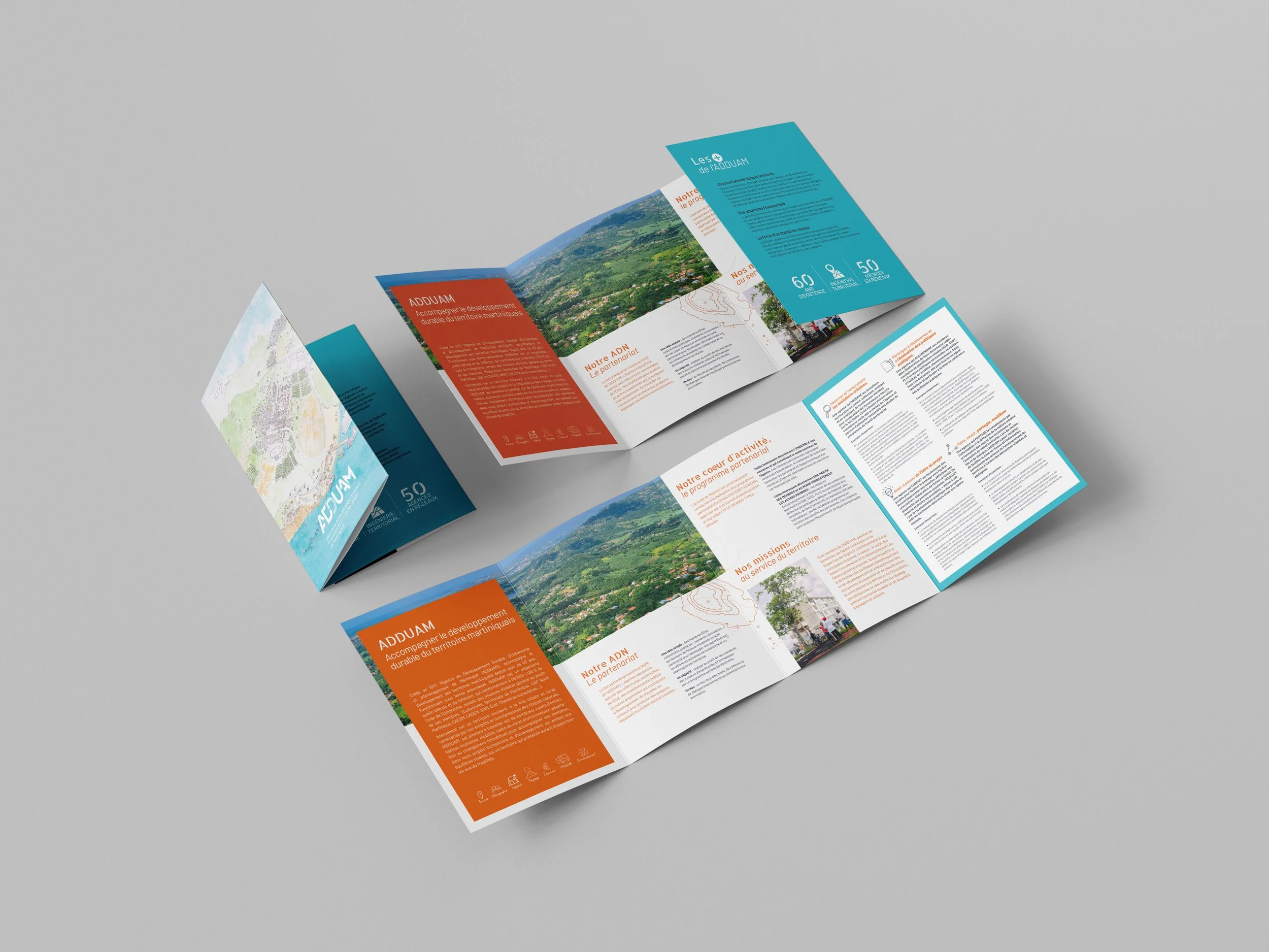 Le dépliant touristique de la région d'ADDUAM avec des couleurs bleues, orange et blanches, présentant des informations et des cartes sur la région entourée de montagnes verdoyantes.