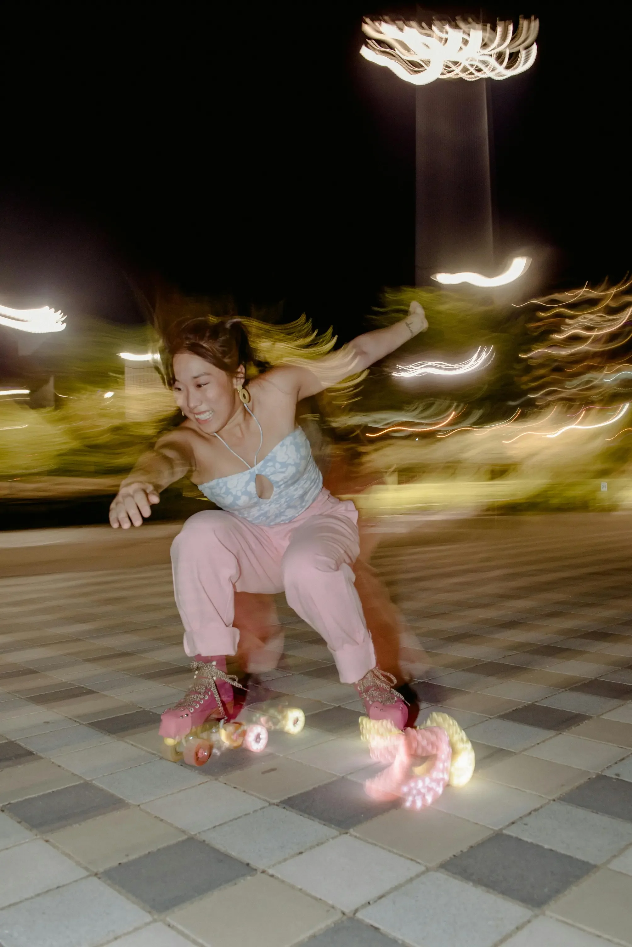 A woman roller skating at night through a city plaza, captured in motion blur with glowing street lights, expressing movement and freedom.
