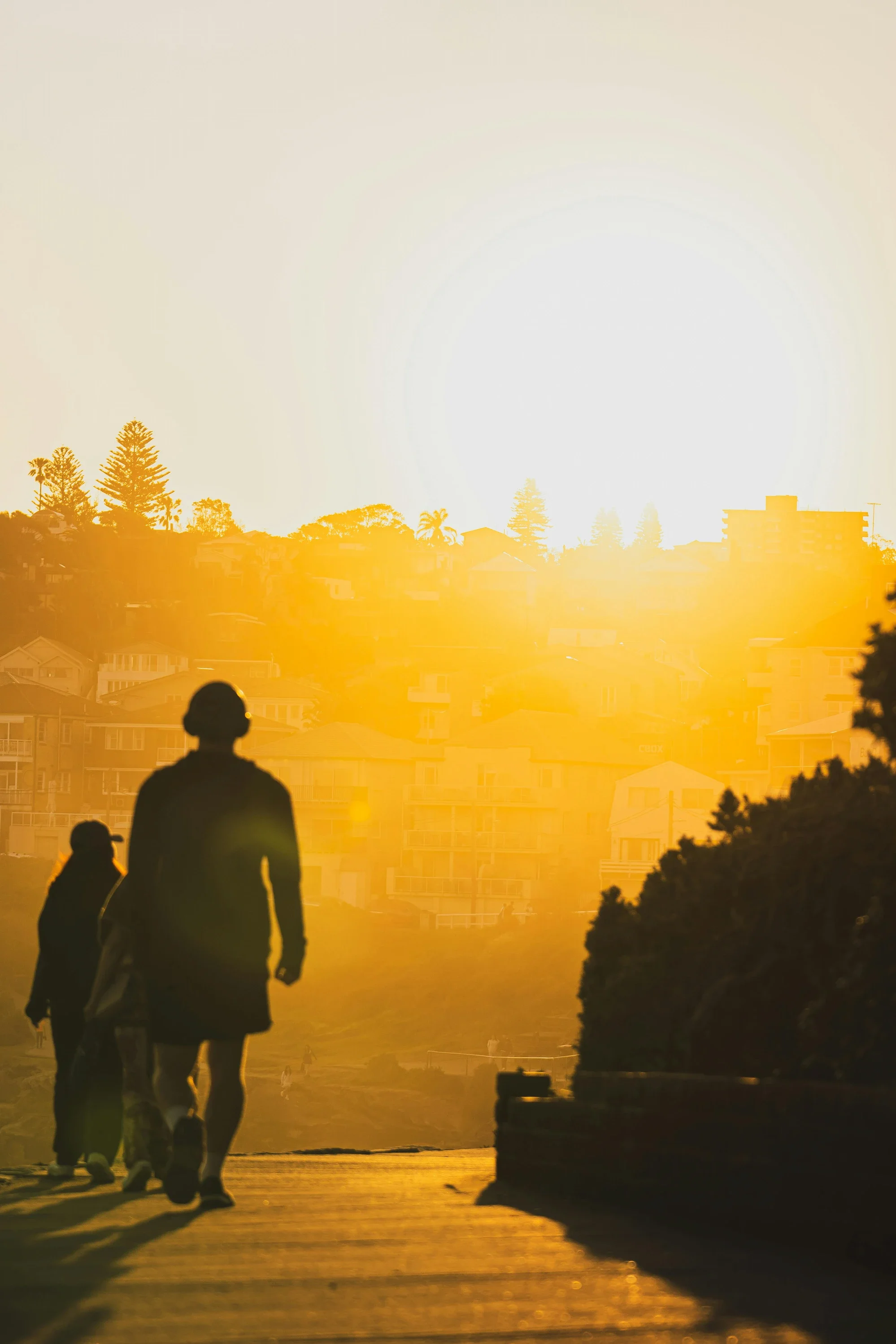 Person walking through warm morning light, symbolizing gentle recovery, regulated energy, and the transition out of survival mode.
