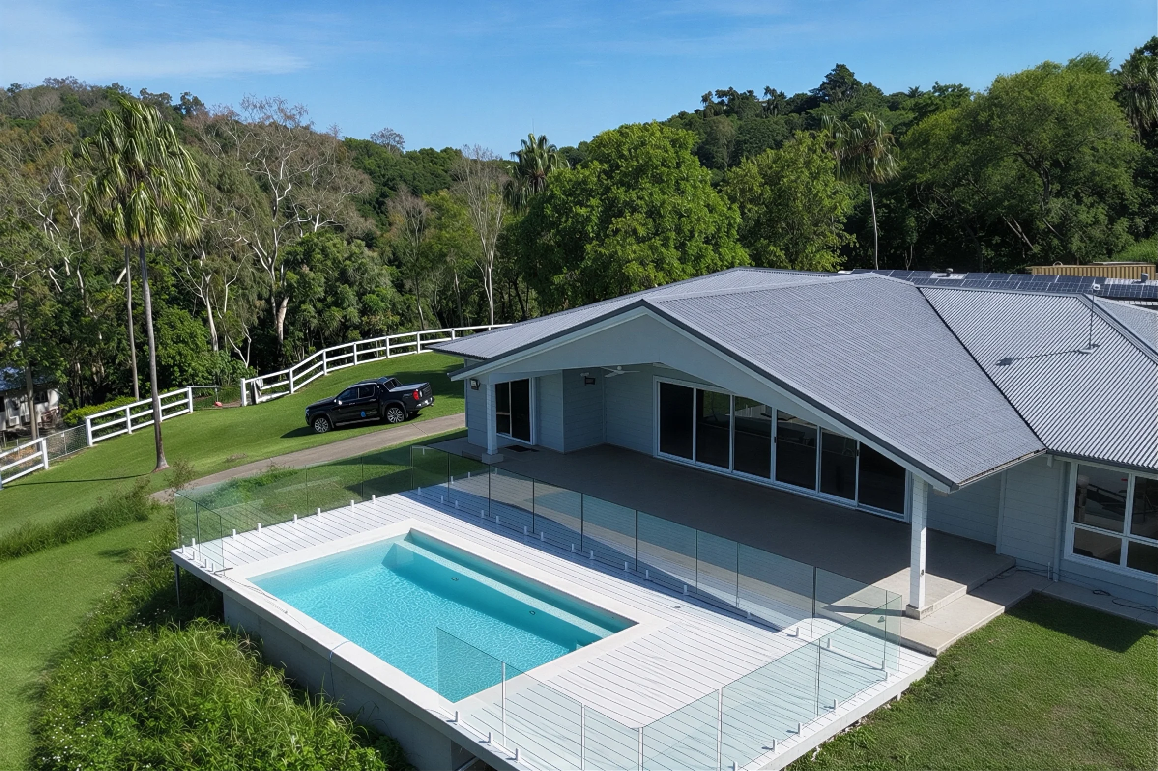 Custom concrete pool showcased in a modern backyard, featuring a sleek rectangular design enclosed by a glass fence.