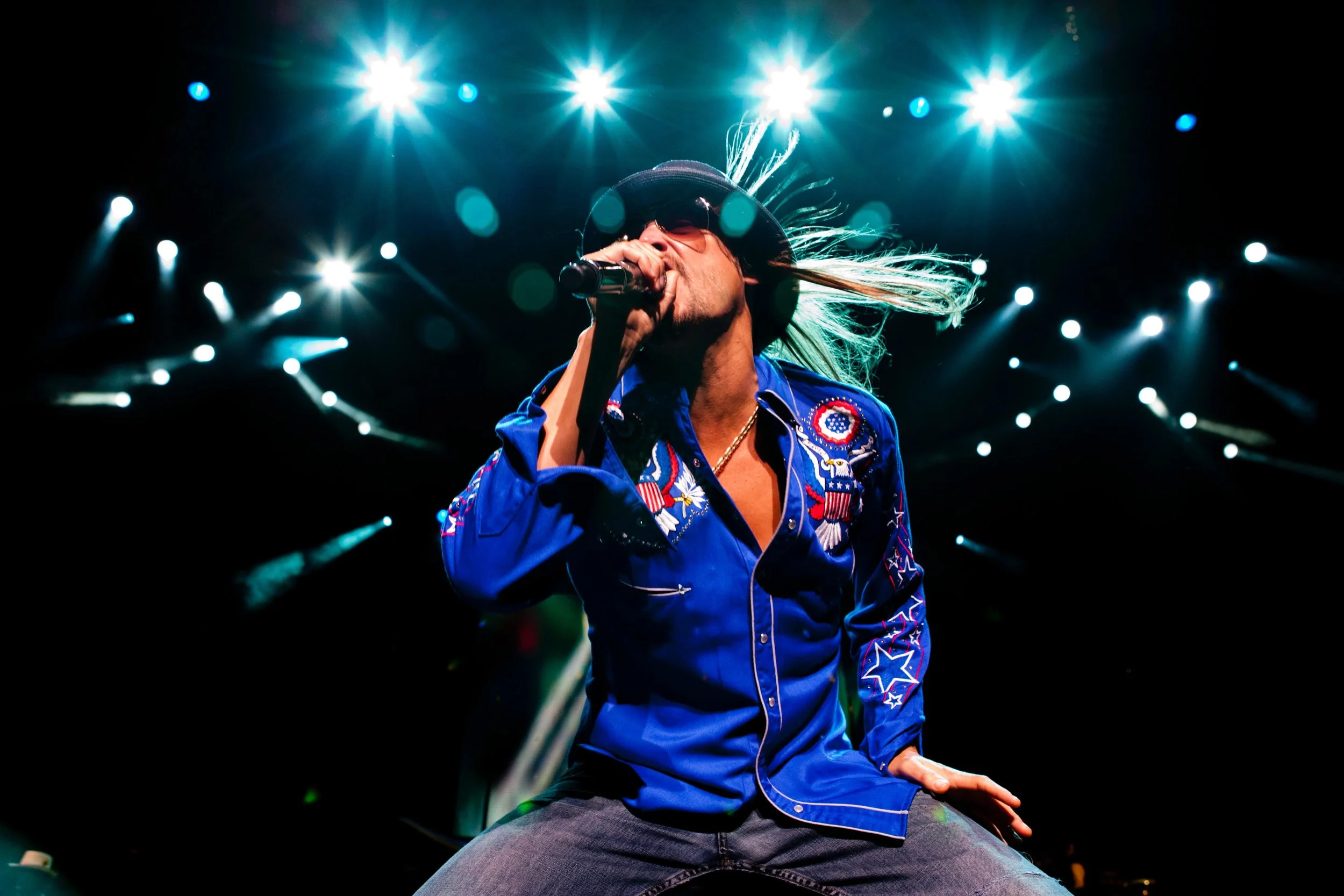 Kid Rock performs on stage under bright spotlights