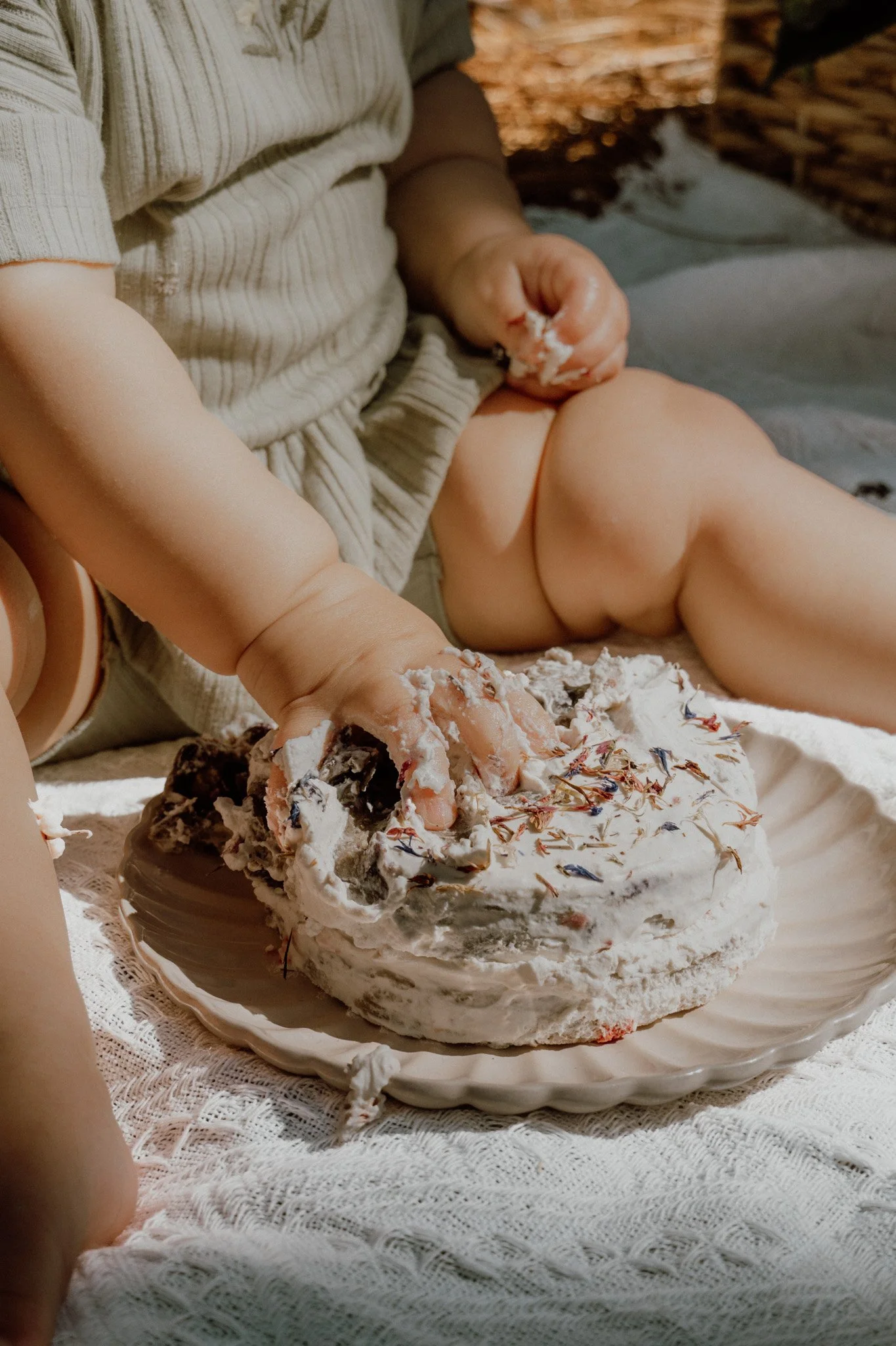Person in striped shirt eating cake with white frosting and chocolate decoration.