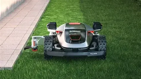 Autonomous lawn mower on a grassy lawn next to a paved walkway.