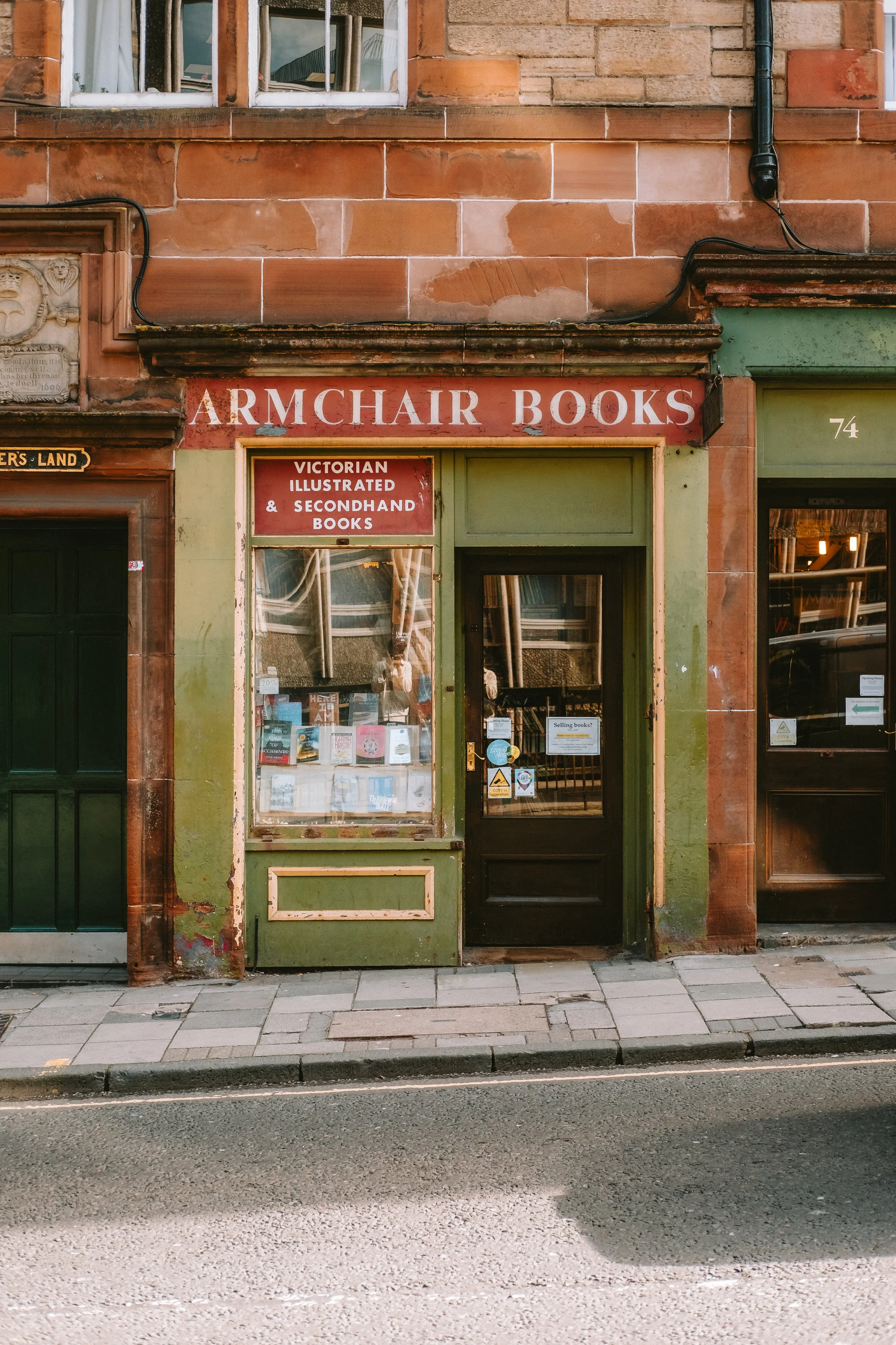 Exterior of Armchair Books, a bookstore with a red sign and green storefront, displaying Victorian illustrated and secondhand books.