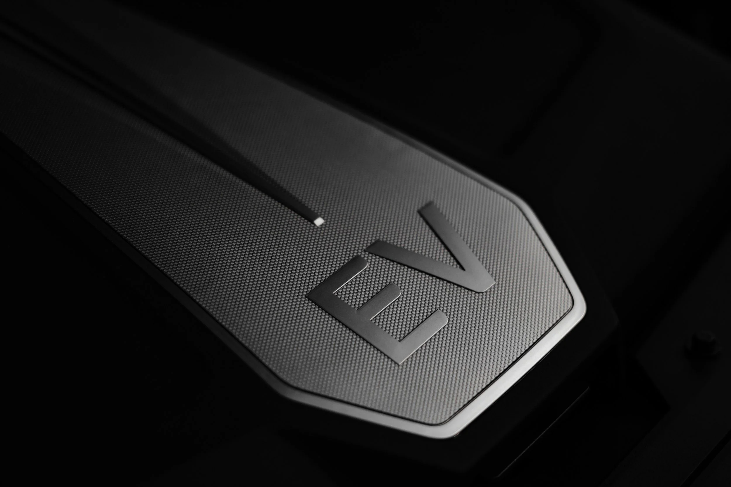 Close-up of a metallic panel with the letters 'V12' engraved on it.