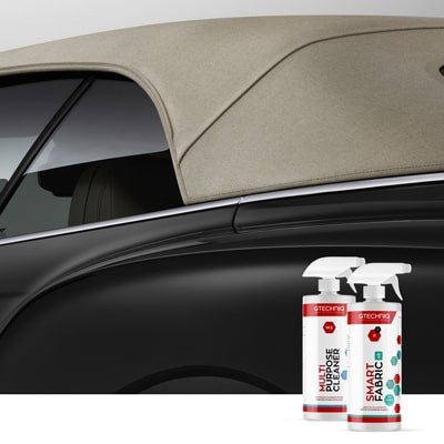 Two bottles of fabric spray, one labeled 'Smart Fabric' and the other 'Double Power,' placed beside a black car with a beige convertible top.