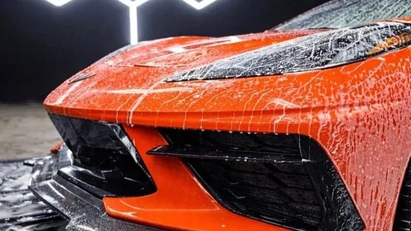 Close-up of a car's front with water droplets and a black grille.