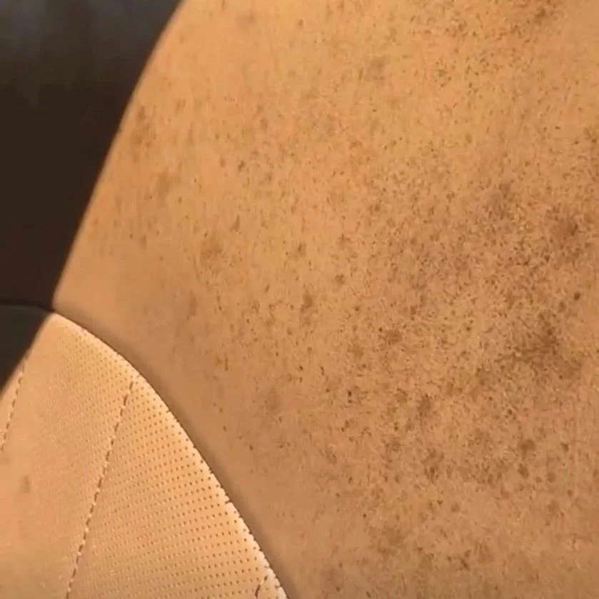 Close-up view of a beige, textured car seat with a pattern of tiny perforations.